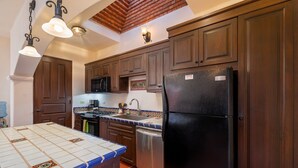 A kitchen with wooden cabinets, a black refrigerator, a microwave, a stove, and a tiled backsplash. - 2BR, 2BA Loreto home with mountain views, community pool, and full kitchen. (Loreto)