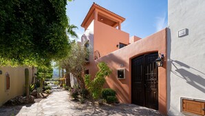 A narrow stone pathway leading to a building with a brown door and a small window. - 2BR, 2BA Loreto home with mountain views, community pool, and full kitchen. (Loreto)