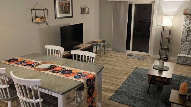Un espace repas comprenant une table, des chaises, un ventilateur de plafond et un téléviseur.