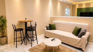 Ein Wohnzimmer mit einer Couch, zwei Sesseln, einem kleinen Tisch und einem Fernseher.