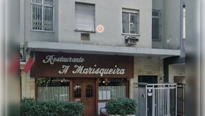 Ein Restaurant namens 'Restaurante A Marisqueira' mit einer braunen Fassade, einer Holztür und Blumentöpfen vor der Tür.