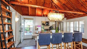 A wooden interior with a dining area, kitchen, and a view through a door. - Lake Simcoe Luxury Cottage | Sauna + Hot Tub (Brechin)