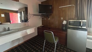A hotel room with a sink, mirror, television, microwave, and a chair. - Big 12 Motel Broken Bow Ne (Broken Bow)