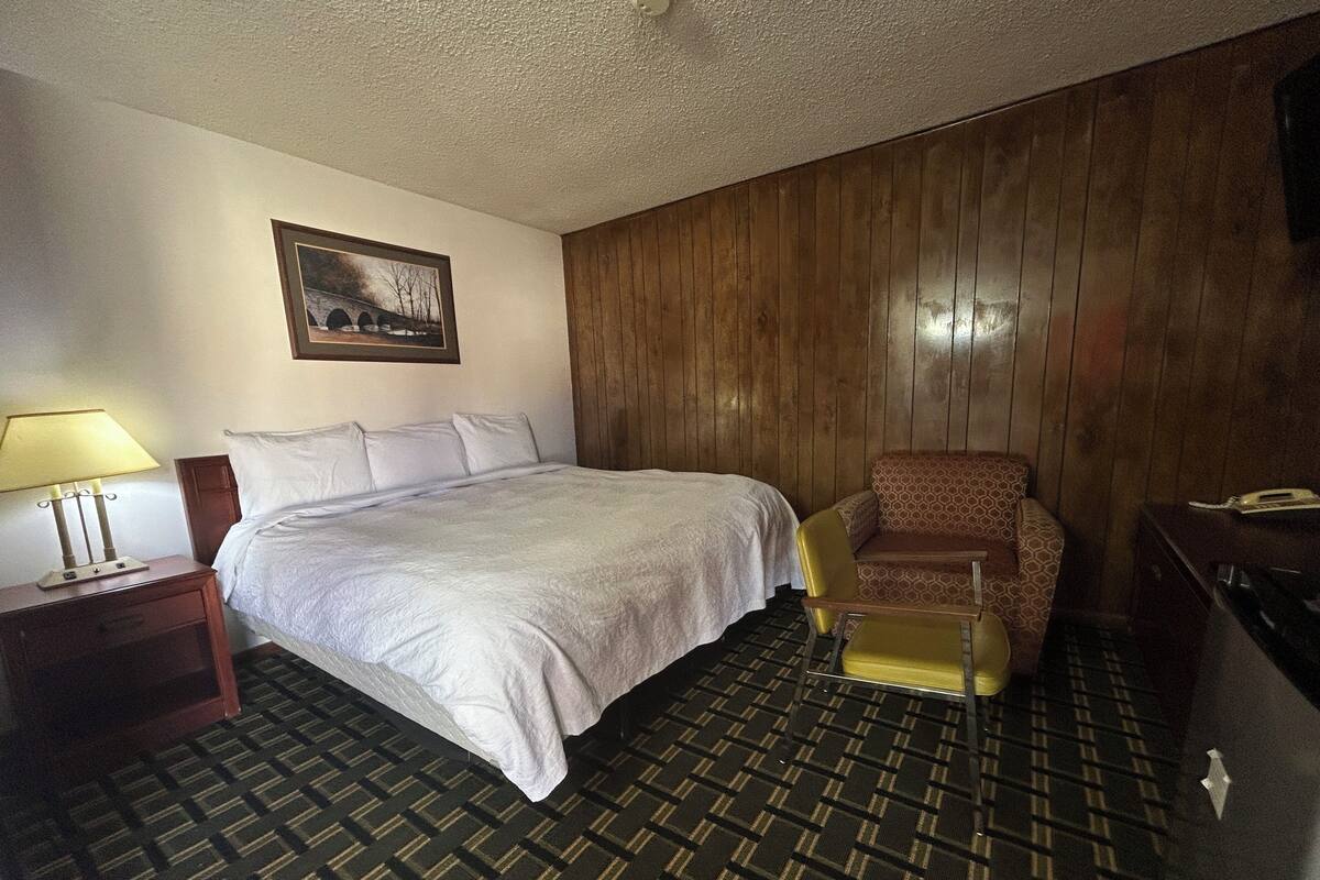Een hotelkamer met een groot bed, een stoel, een bureau en een lamp.