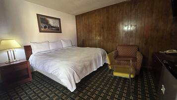 Una habitación de hotel con una cama grande, una silla, un escritorio y una lámpara.