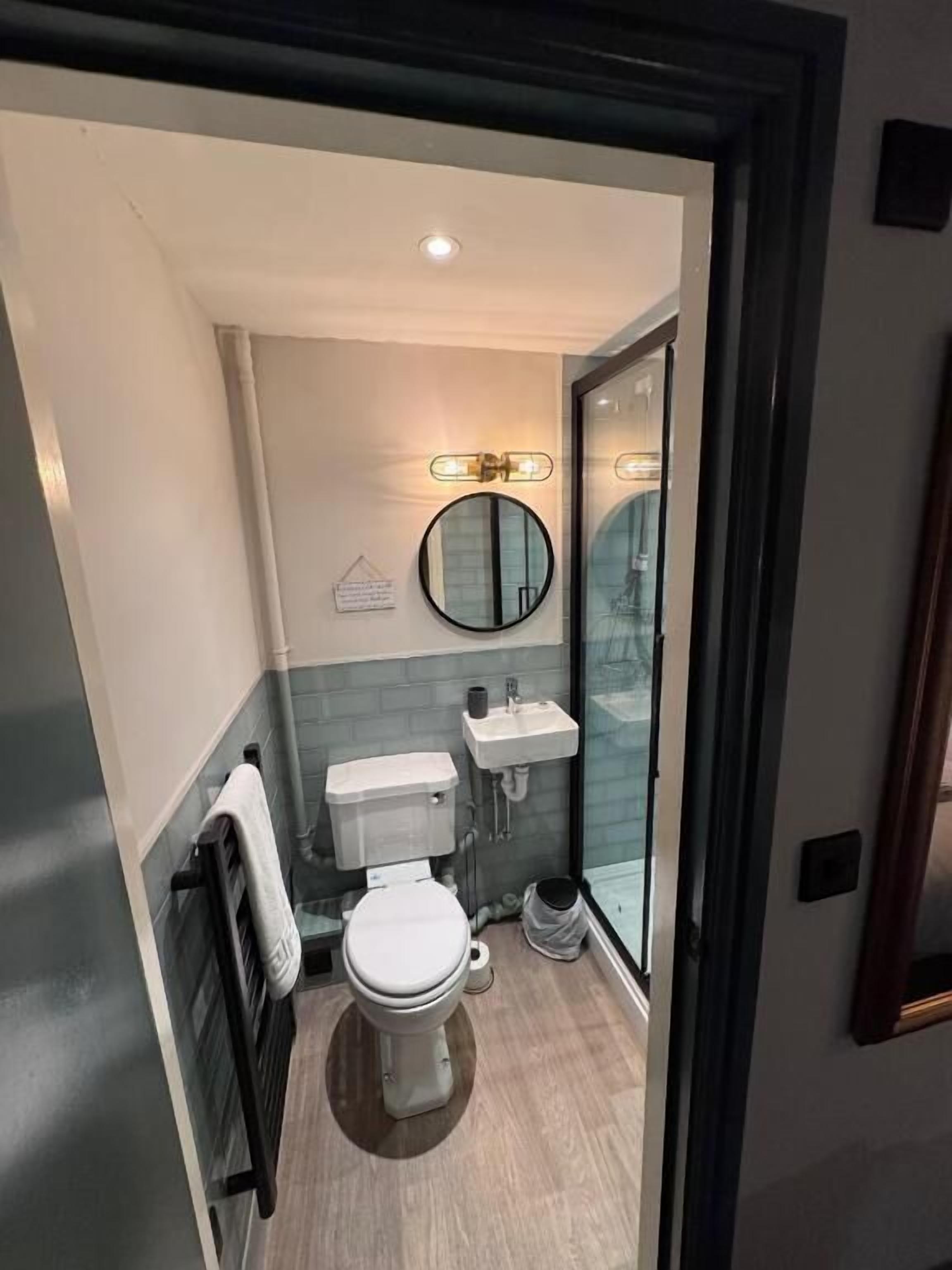 A compact bathroom with a toilet, sink, and mirror.