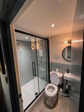 A modern bathroom with a glass-enclosed shower, a toilet, and a sink. - OYO White Bear at Bedale (Bedale)