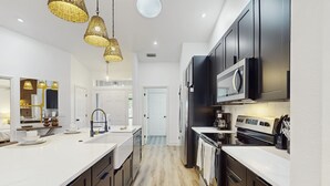 A modern kitchen with dark cabinets, a large island, and a microwave. - Luxury Waterfront Escape with Heated Pool, Hot Tub, & Outdoor Patio! 🌊 (Melbourne)