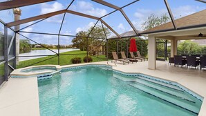 A swimming pool with a glass enclosure, surrounded by lounge chairs and a patio area. - Luxury Waterfront Escape with Heated Pool, Hot Tub, & Outdoor Patio! 🌊 (Melbourne)