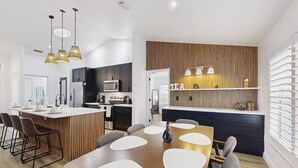 A modern kitchen with dark cabinets, a central island, and pendant lighting. - Luxury Waterfront Escape with Heated Pool, Hot Tub, & Outdoor Patio! 🌊 (Melbourne)