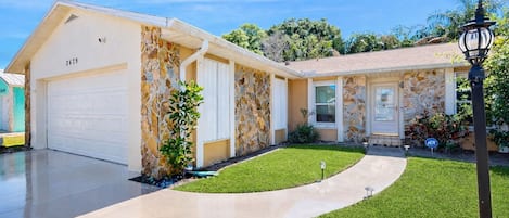 Una casa de dos plantas con garaje, fachada de piedra y césped cuidado.