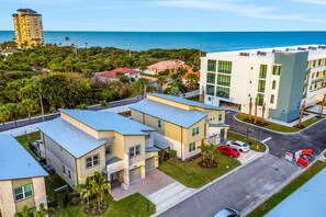 Un complejo residencial moderno con varios edificios, un estacionamiento y vista al océano.