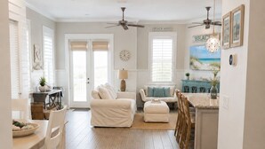 A spacious living area with a dining table, two sofas, a coffee table, and a kitchen area with a countertop and cabinets. - Gorgeous Home in 30A - Golf Cart + Bikes Included (Santa Rosa Beach)