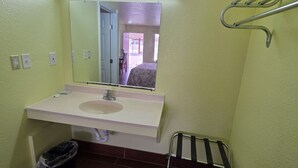Un baño pequeño con un lavamanos blanco, un espejo, un perchero para toallas y un cubo de basura.