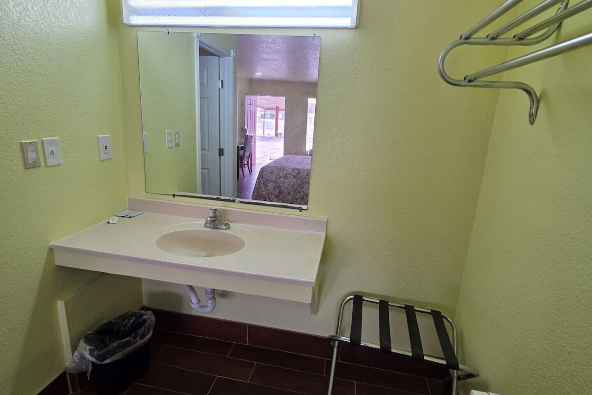 A small bathroom with a white sink, a mirror, a towel rack, and a trash bin.