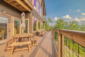 A wooden deck with outdoor seating and a view of the surrounding landscape. - Cabin with Breathtaking Views, Hot Tub & Game Room (Sevierville)