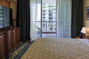 A hotel room with a bed, a dresser, a television, and a balcony with a view of buildings. - Suarez Art Stay, Scenic Miami View, Gym, Park (Miami)