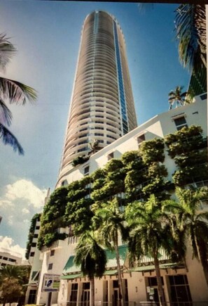 A tall, cylindrical building with a modern design, surrounded by palm trees and a clear sky. - Suarez Art Stay, Scenic Miami View, Gym, Park (Miami)