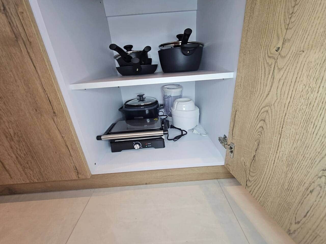 Eine Küche mit Kaffeemaschine, Reiskocher und einem schwarzen Gerät auf der Arbeitsfläche.