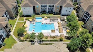 Un complejo residencial con piscina central, varios balcones y abundante vegetación.
