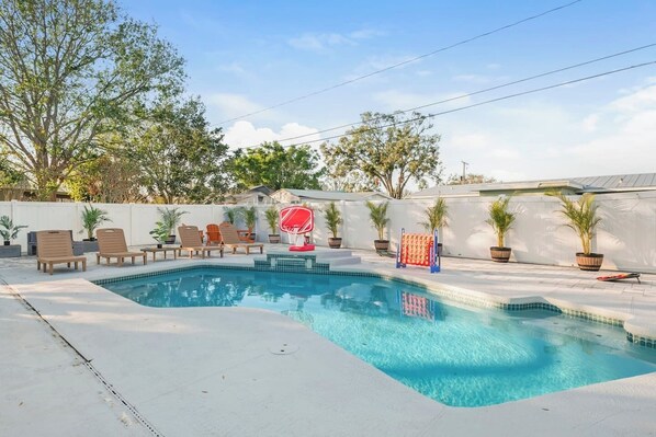 A rectangular swimming pool with a basketball hoop, lounge chairs, and potted plants. - Newly Remodeled Lush Boho Vibe (Apollo Beach)