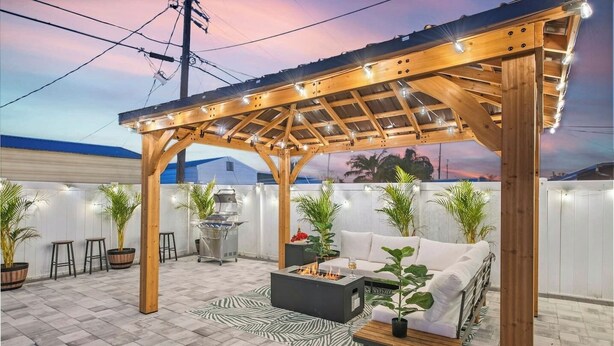 A covered outdoor patio with a grill, seating area, and string lights. - Newly Remodeled Lush Boho Vibe (Apollo Beach)