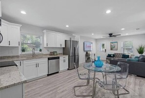 A modern kitchen with white cabinets, stainless steel appliances, and a glass dining table with chairs. - Stylish in heart of Tampa 2bed/2bath Close to YBOR (Tampa)