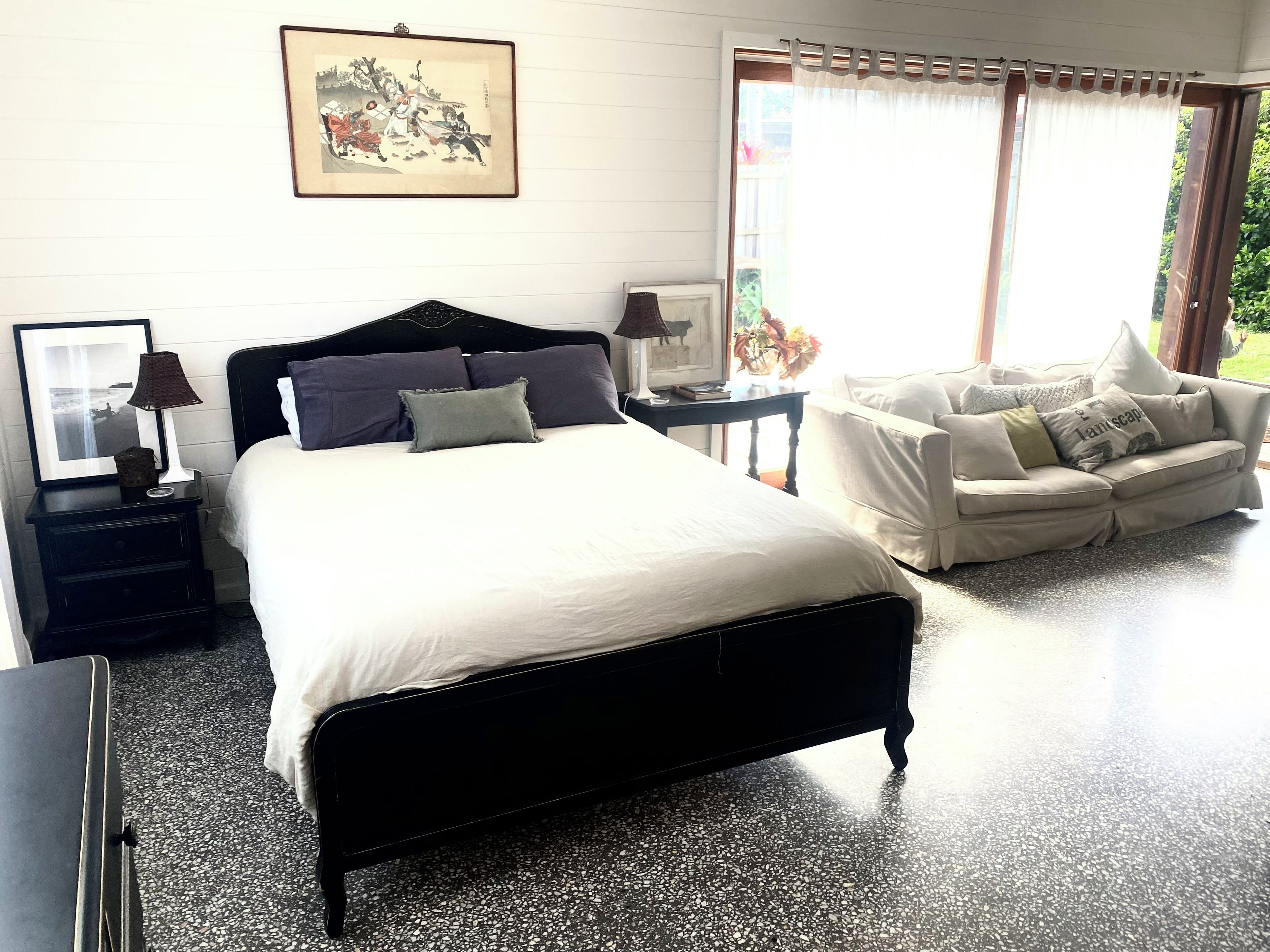 Bright, spacious bedroom with cozy sitting area and large sunny windows