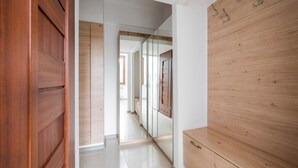 Un pasillo con piso de madera, un armario de madera y una puerta de closet con espejo.