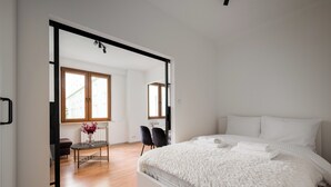 Un dormitorio moderno con una cama grande, una mesa de vidrio y una silla.