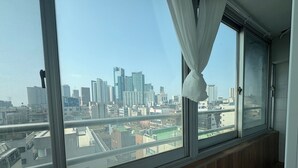 A room with a large window overlooking a cityscape with high-rise buildings. - K wave guesthouse only Female 2 (Seoul)