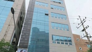 A modern building with multiple floors, large windows, and a sign for JS BLDG. - K wave guesthouse only Female 2 (Seoul)