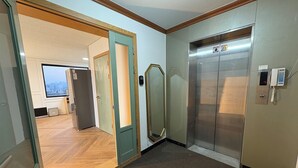 An elevator, a door, and a view of a cityscape through a window. - K wave guesthouse only Female 2 (Seoul)