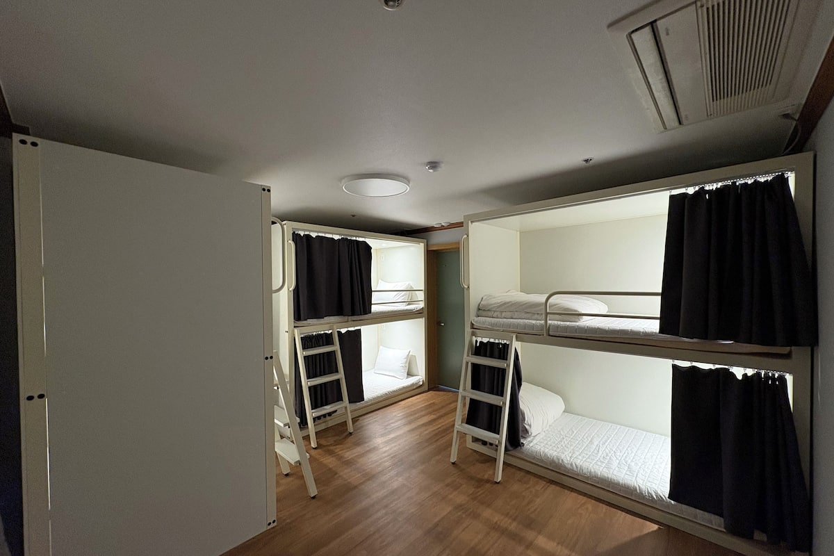 A room with bunk beds, a ladder, and a door.