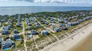 Luchtbeeld van een kustgebied met woonhuizen, een strand en water.