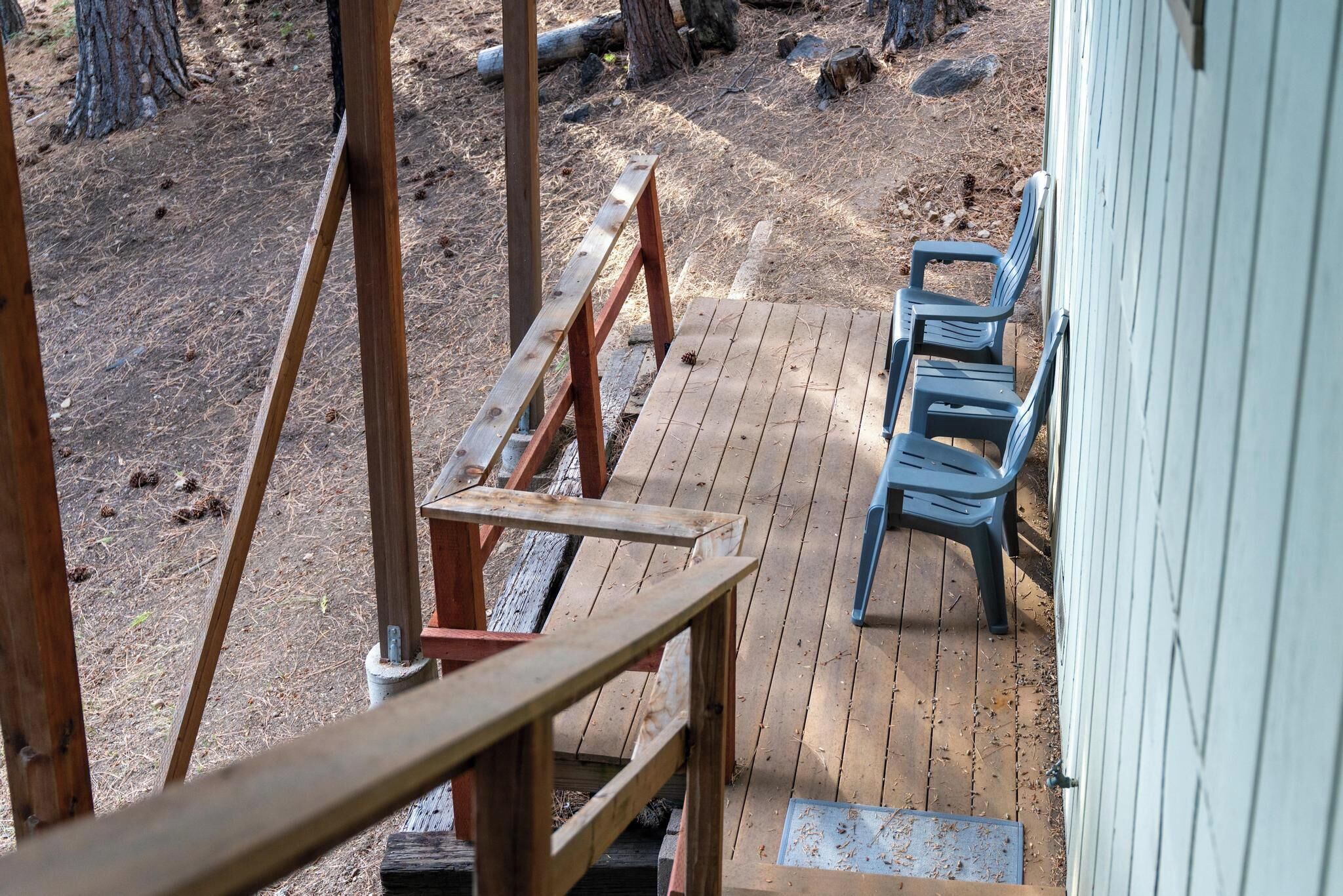 Une terrasse en bois, dotée de bancs et d’un escalier en bois menant à un bâtiment.