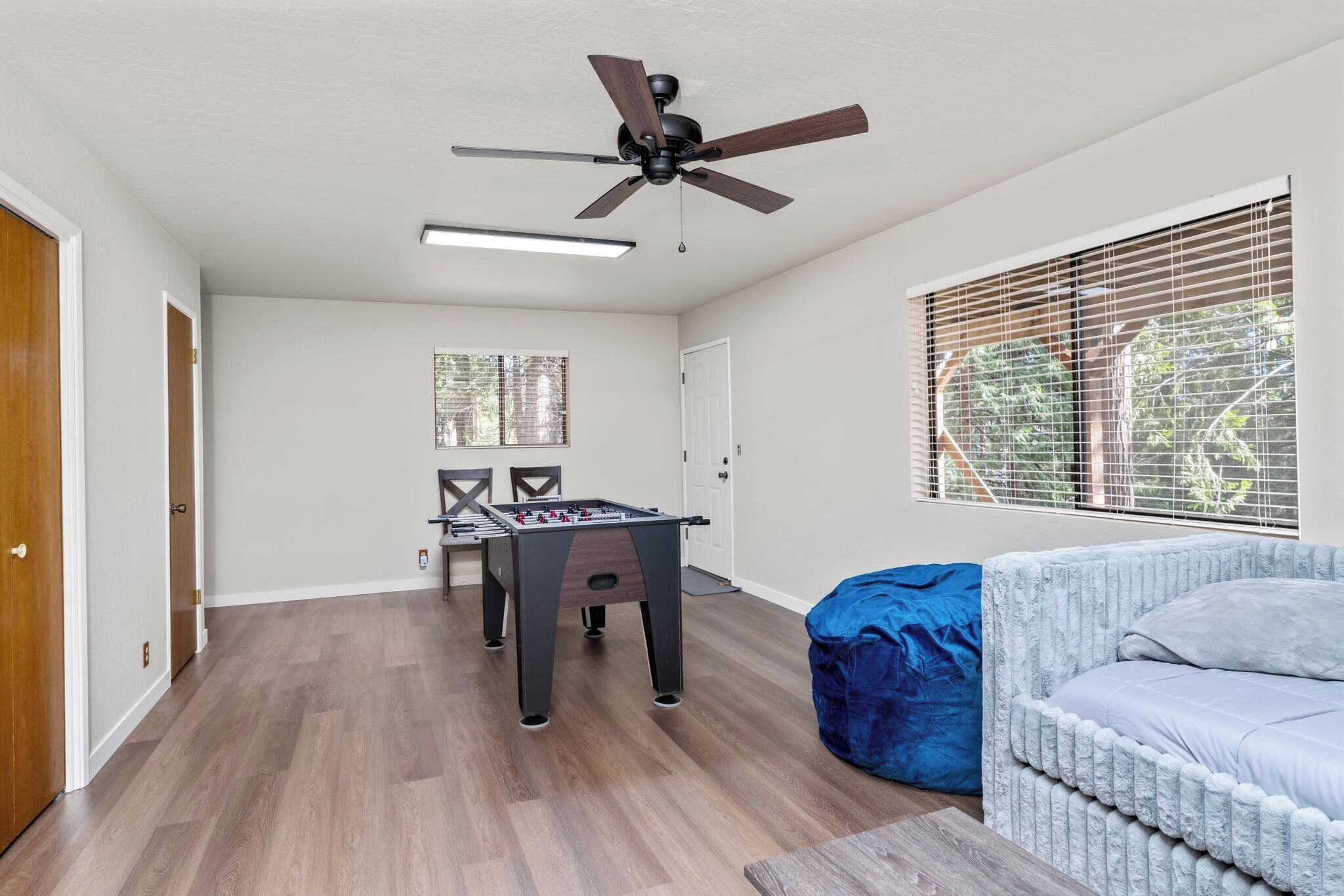 Ein Zimmer mit Kicker, Deckenventilator und einem Fenster mit Jalousien.