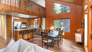Una cocina amplia con armarios de madera, una isla grande con taburetes de bar y un comedor con mesa y sillas de madera.