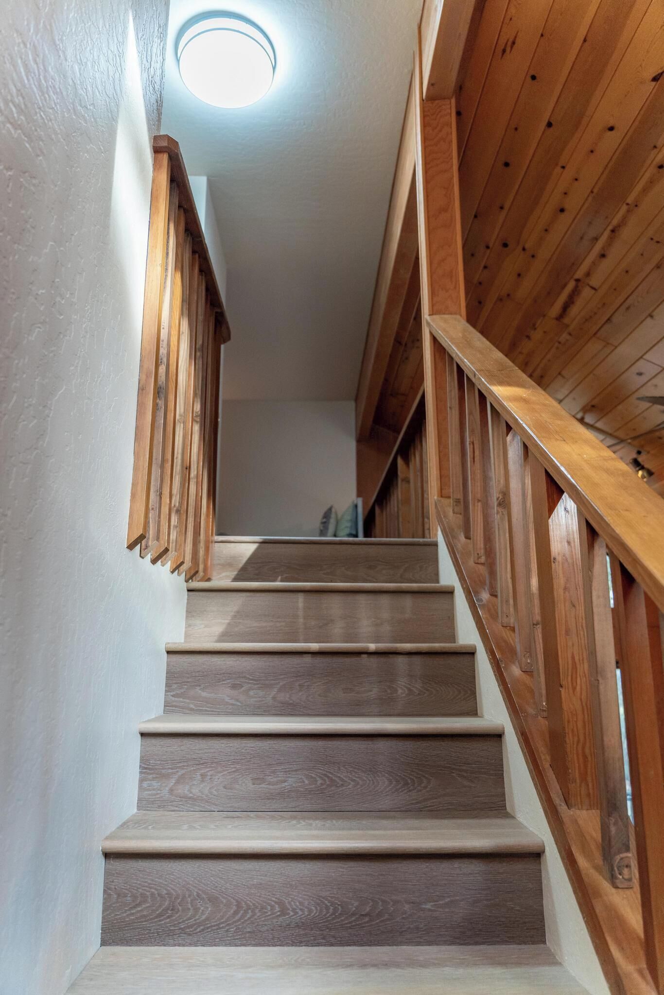 Un escalier en bois avec un luminaire au-dessus.