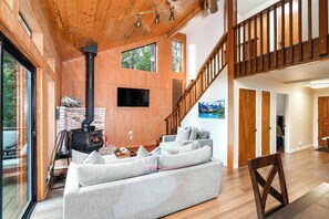Ein modernes Wohnzimmer mit Kamin aus Stein, einem großzügigen Ecksofa und einer Holztreppe.