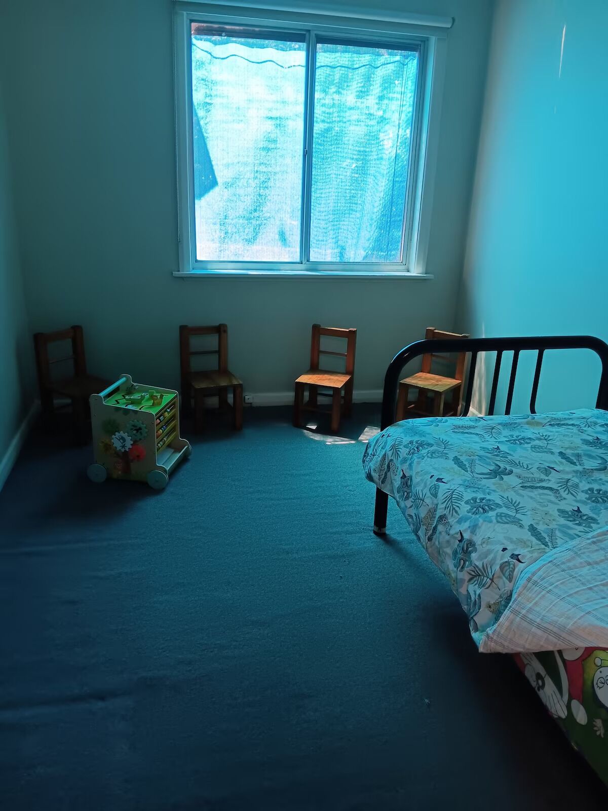 Ein Kinderzimmer mit einem Bett, einem kleinen Schreibtisch und einem Fenster.