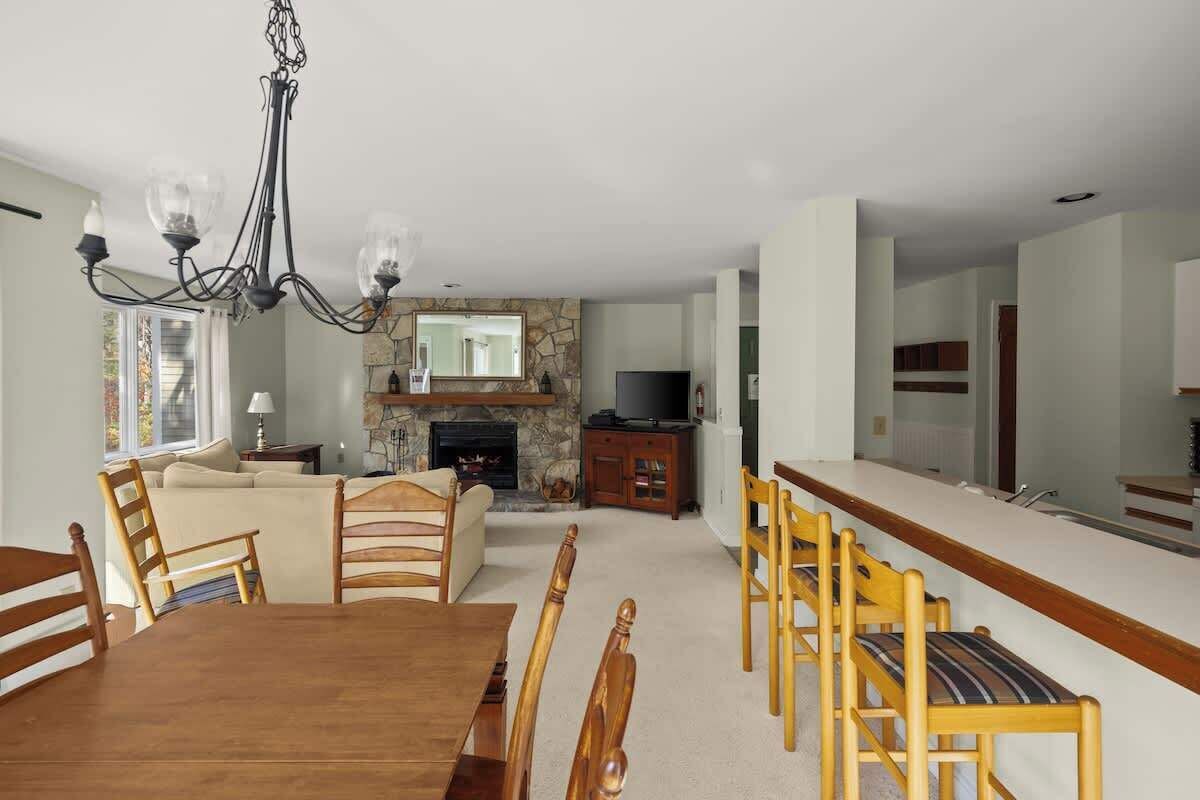 A dining area with a wooden table and chairs, a stone fireplace, and a television.