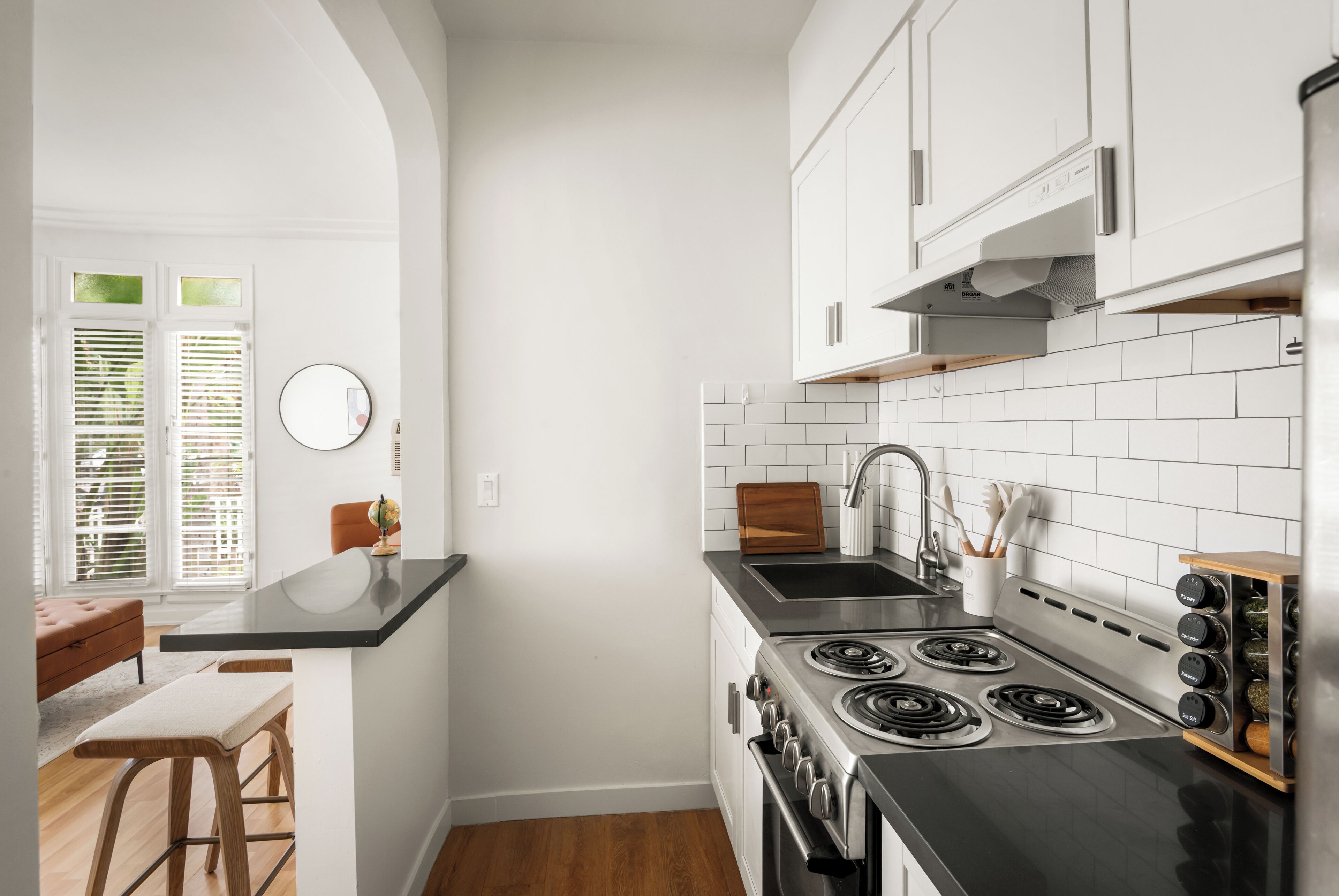Une cuisine moderne avec des meubles blancs, un plan de travail noir et une cuisinière.