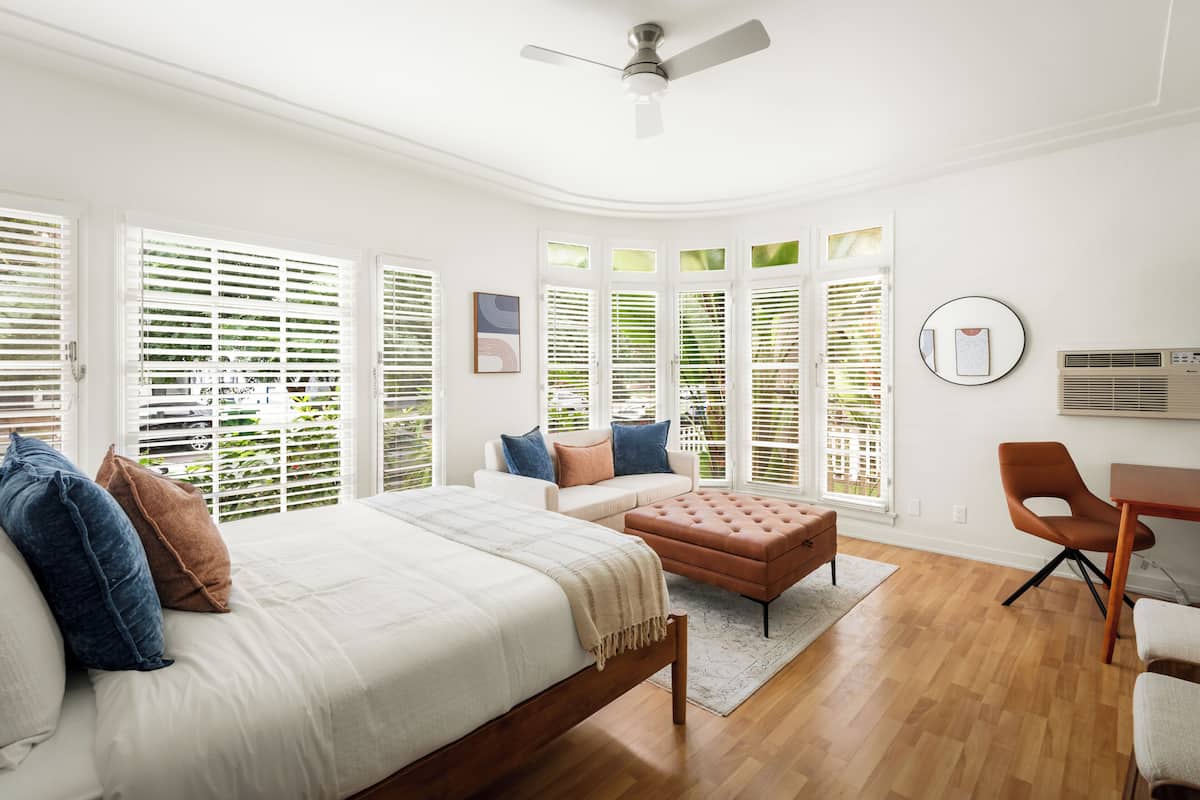 A bedroom with a bed, a sofa, a coffee table, and a desk.