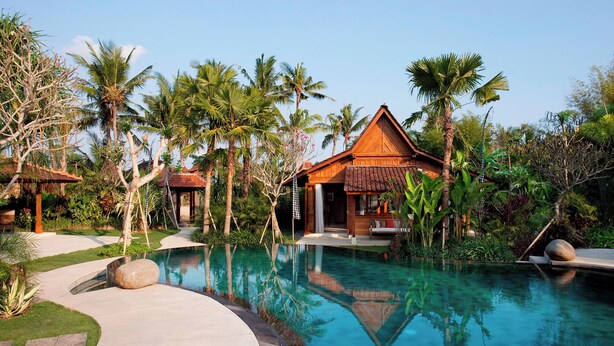 Ein Resort mit Schwimmbad, Holzhäusern und tropischer Vegetation.
