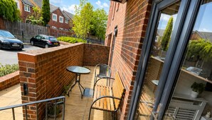 A balcony with a table and chairs, a brick wall, and a glass door. - The Grounded Pearl (Salford)