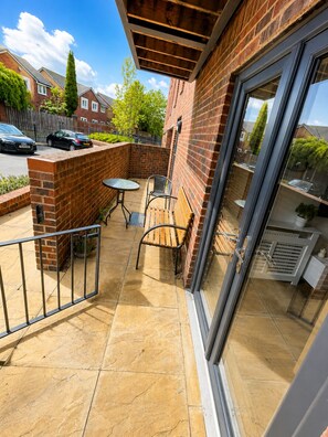A balcony with a table and chairs, a brick wall, and a glass door. - The Grounded Pearl (Salford)