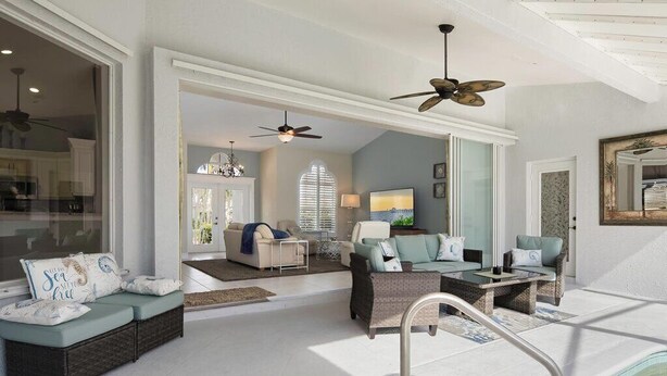 A spacious living area with a pool, ceiling fans, and a view of the kitchen. - Beautiful vacation home with great lake view and pool in Naples (Naples)