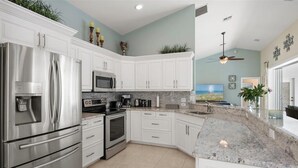 A modern kitchen with white cabinets, stainless steel appliances, and a granite countertop. - Beautiful vacation home with great lake view and pool in Naples (Naples)