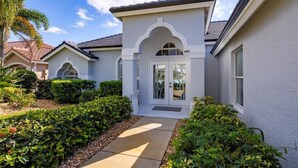 A two-story house with a white exterior, a front entrance with glass doors, and a small porch area. - Beautiful vacation home with great lake view and pool in Naples (Naples)